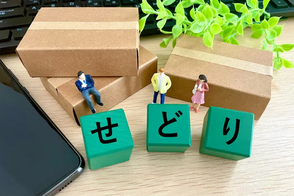 せどりの文字の前に立つ3人のビジネスパーソンと梱包された荷物３つ