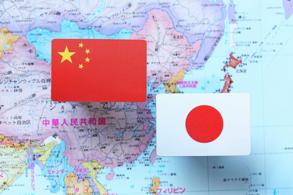 世界地図の上に中国と日本の国旗がのっている