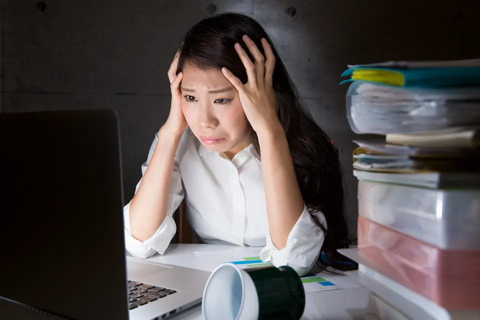 PCの前で頭を抱え込む女性