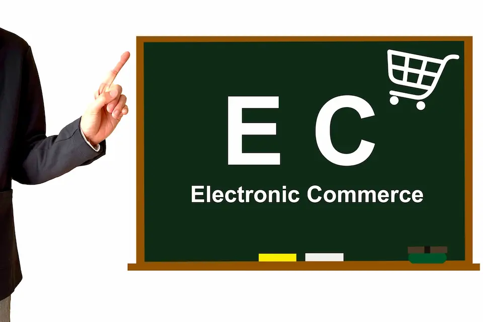 黒板にEC の文字を指さすビジネスマン