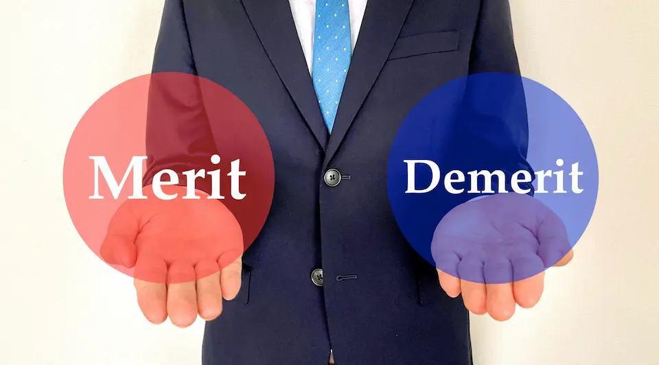 ビジネスマンの両手にメリットとデメリットの文字