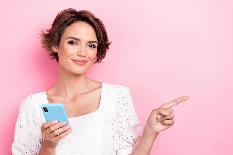 スマホ片手に指をさす女性