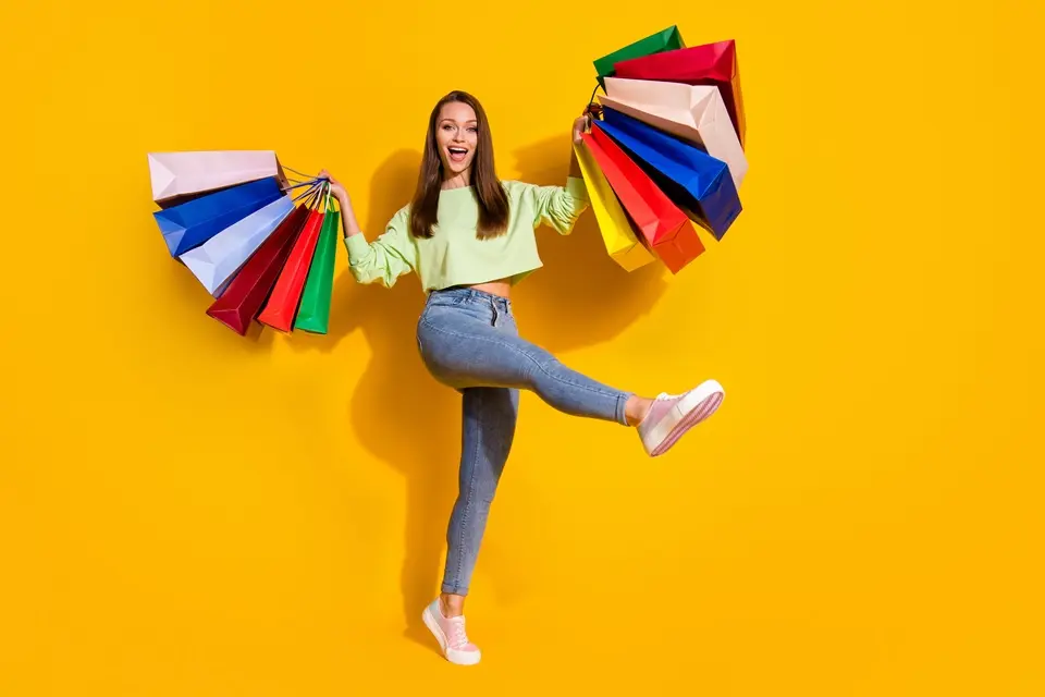 多くのカラフルなショッピングバックを両手に持ちスキップする女性