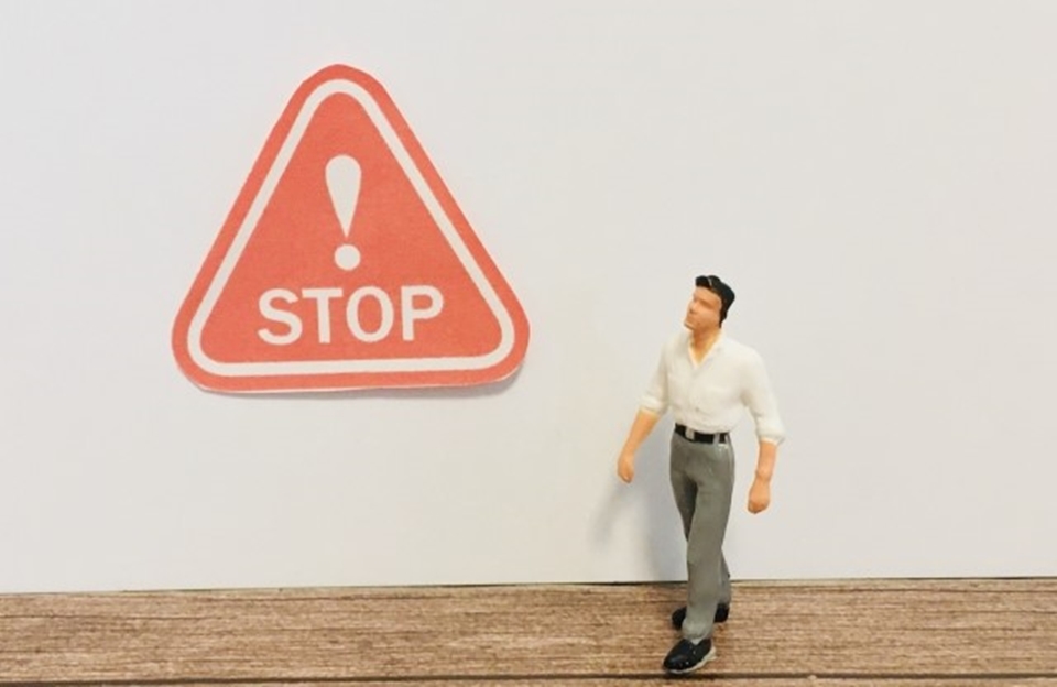 STOPの標識とそれを見上げる男性