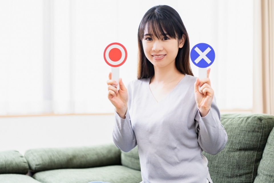 〇とXのマークを手にする女性