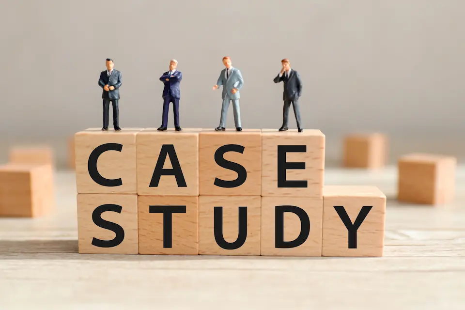 積み木にCASE STUDYと書かれた文字と、その上に立つ4人のビジネスマン