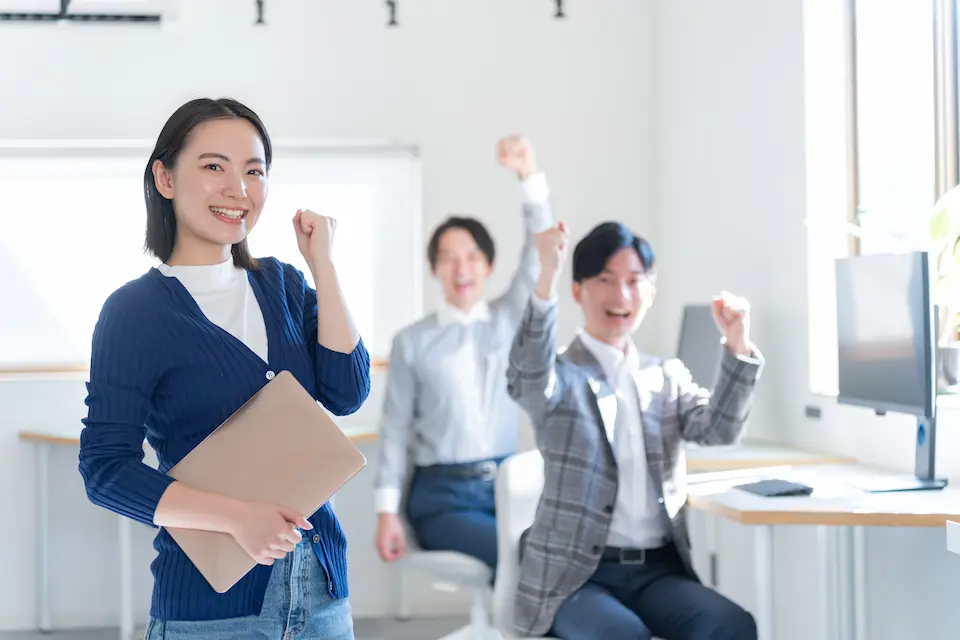 オフィスでガッツポーズをとる３人の男女