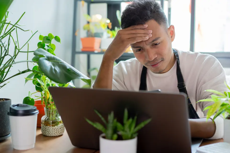 花屋でPCへ向かって頭をかかえる男性